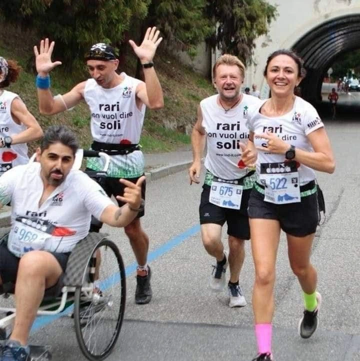 Spingitore Francesco Mininni in azione dinamica durante evento sportivo inclusivo con carrozzina.